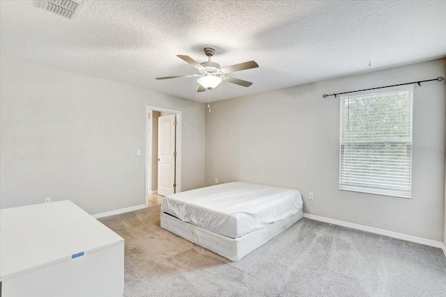 bedroom featuring ceiling fan, light colored carpet, and a textured ceiling