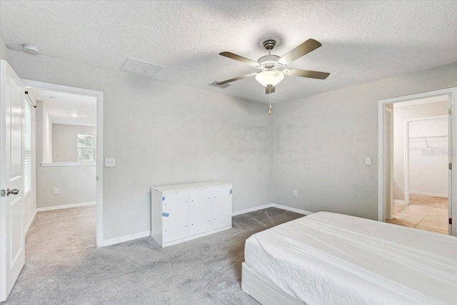 bedroom with ceiling fan, carpet flooring, and a textured ceiling