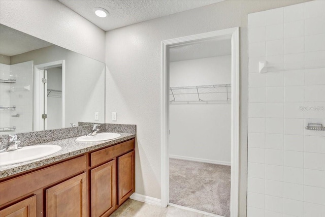 bathroom featuring vanity, a shower, and a textured ceiling