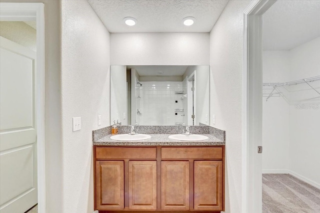 bathroom with vanity, a tile shower, and a textured ceiling