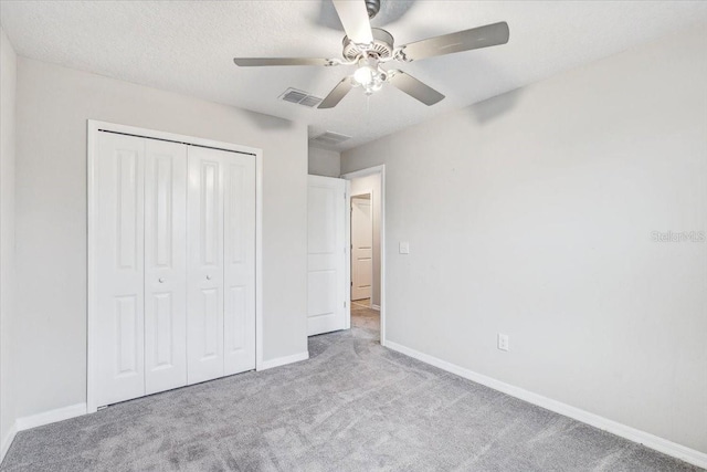 unfurnished bedroom with ceiling fan, a closet, light carpet, and a textured ceiling