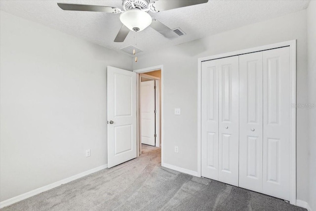 unfurnished bedroom with ceiling fan, light carpet, a textured ceiling, and a closet