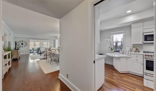 kitchen featuring white range oven, white cabinets, a textured ceiling, and light wood-type flooring