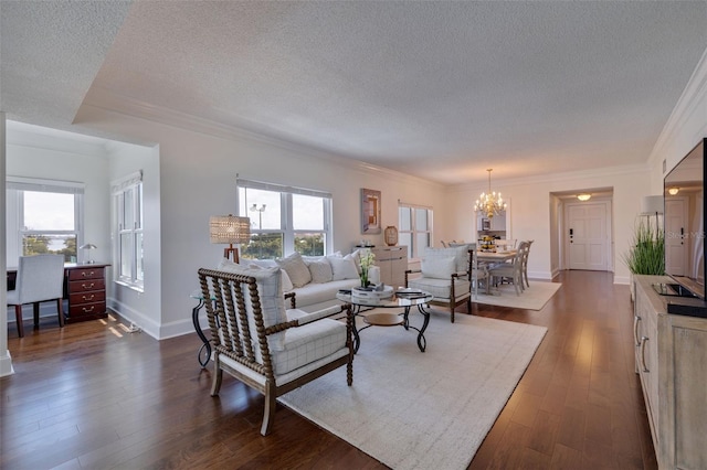 living room featuring a notable chandelier, ornamental molding, dark hardwood / wood-style floors, and a textured ceiling