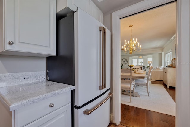 kitchen with light stone countertops, hardwood / wood-style flooring, white cabinetry, high end white refrigerator, and ornamental molding