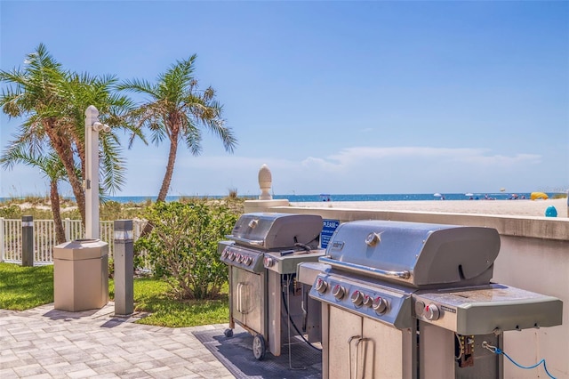 view of patio / terrace with a water view, an outdoor kitchen, grilling area, and a beach view