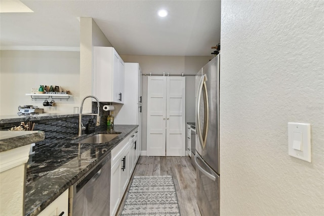 kitchen featuring white cabinetry, dark stone counters, sink, light hardwood / wood-style flooring, and stainless steel appliances