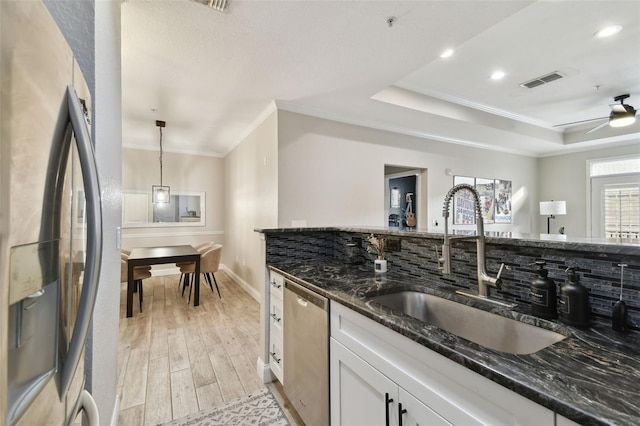 kitchen featuring white cabinets, appliances with stainless steel finishes, a raised ceiling, and dark stone countertops