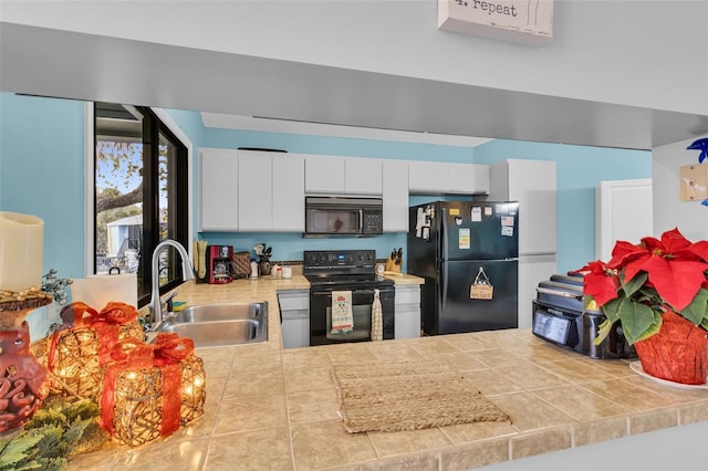 kitchen featuring black appliances, white cabinetry, tile counters, and sink