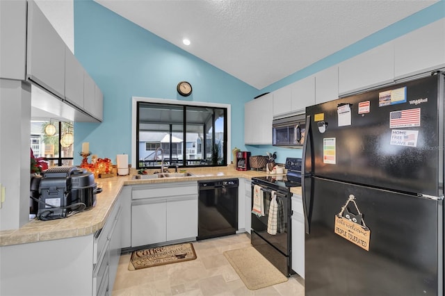 kitchen with sink, white cabinetry, black appliances, and vaulted ceiling