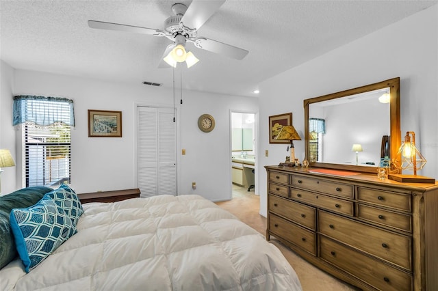 carpeted bedroom featuring ceiling fan, connected bathroom, a closet, and a textured ceiling