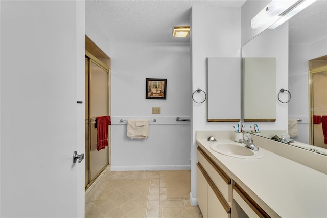 bathroom featuring vanity, a shower with shower door, tile patterned floors, and a textured ceiling