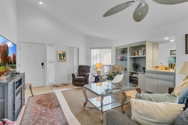 living room with high vaulted ceiling, built in features, and ceiling fan