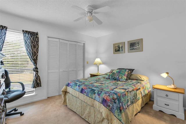 carpeted bedroom featuring a closet, ceiling fan, and a textured ceiling