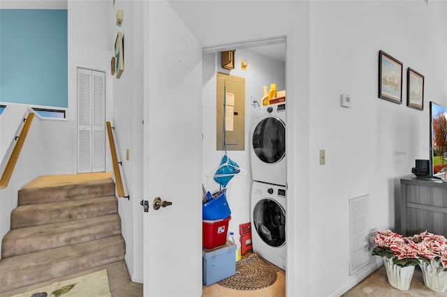 laundry area with stacked washer / drying machine and electric panel