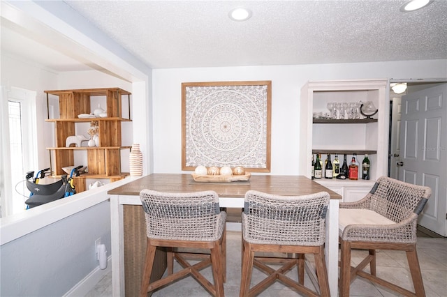 dining space featuring light tile patterned floors and a textured ceiling