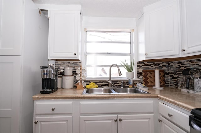 kitchen featuring decorative backsplash, electric range, sink, and white cabinetry