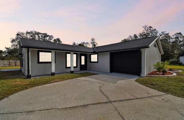 ranch-style house featuring a garage and a lawn