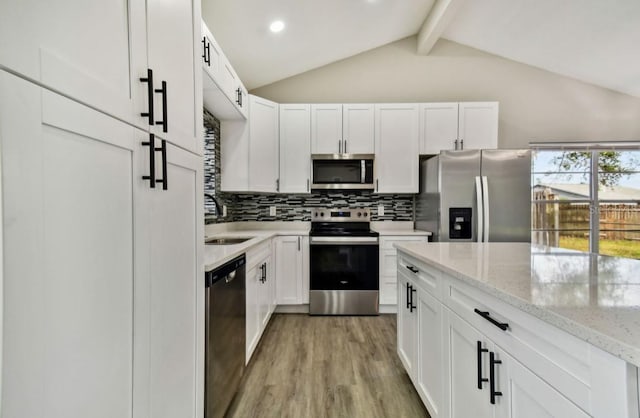 kitchen featuring vaulted ceiling with beams, white cabinetry, light hardwood / wood-style flooring, stainless steel appliances, and light stone counters