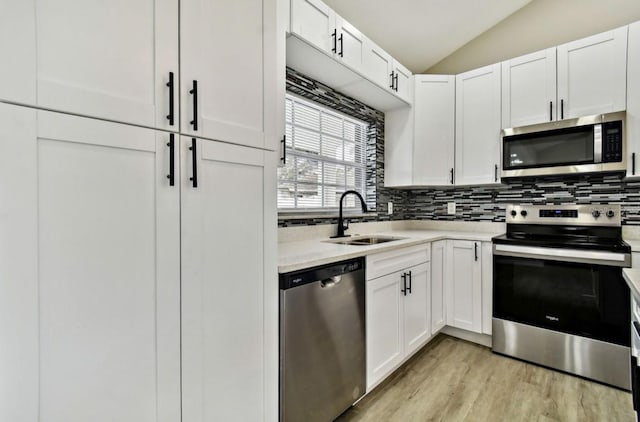 kitchen featuring lofted ceiling, light hardwood / wood-style floors, sink, appliances with stainless steel finishes, and white cabinets