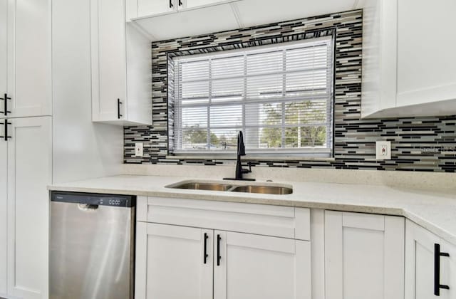 kitchen with light stone counters, sink, white cabinets, and dishwasher