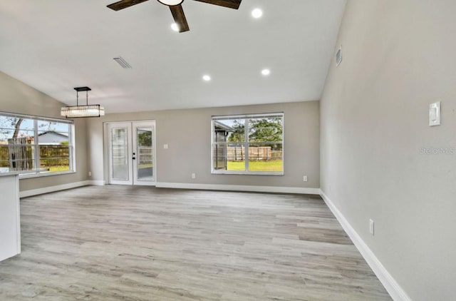 unfurnished living room featuring light wood-type flooring, lofted ceiling, plenty of natural light, and french doors