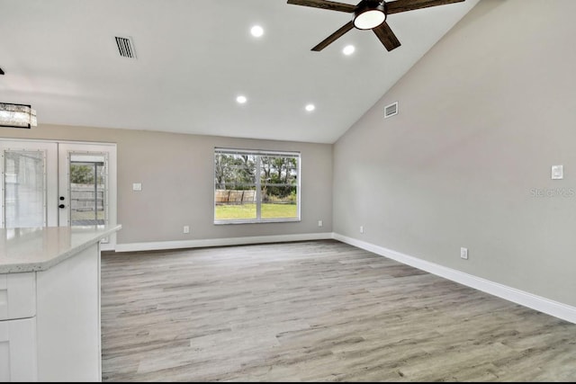 unfurnished living room with ceiling fan, high vaulted ceiling, french doors, and light wood-type flooring