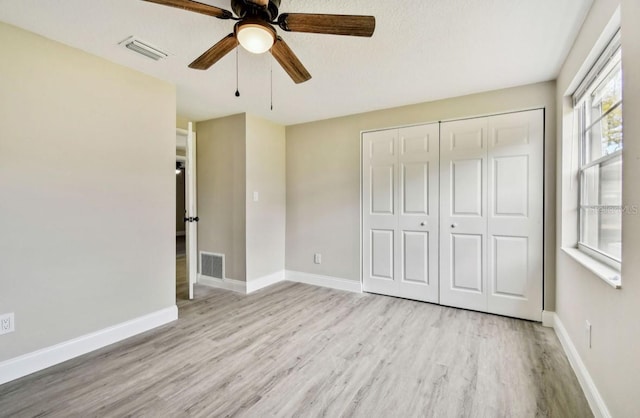 unfurnished bedroom with light wood-type flooring, ceiling fan, a closet, and multiple windows