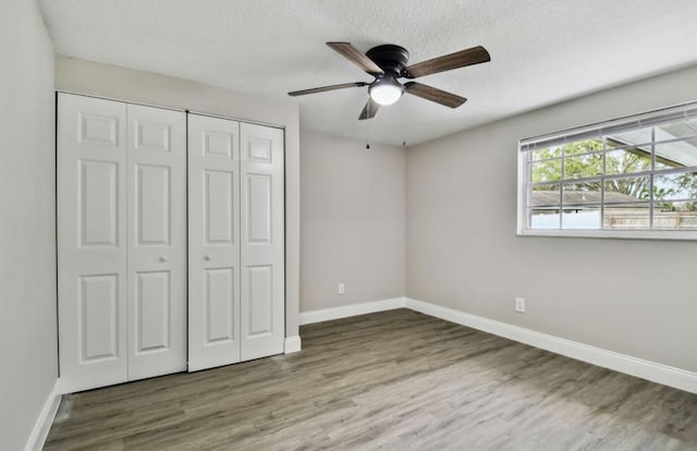 unfurnished bedroom featuring a textured ceiling, ceiling fan, a closet, and dark hardwood / wood-style floors