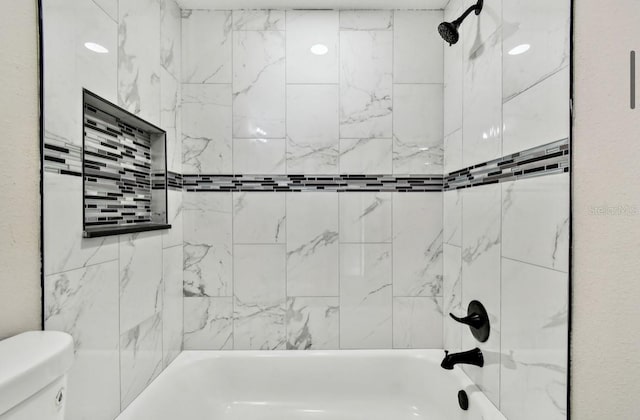 bathroom featuring toilet and tiled shower / bath