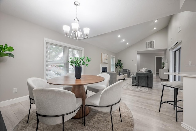 dining area with a chandelier, light hardwood / wood-style flooring, and lofted ceiling