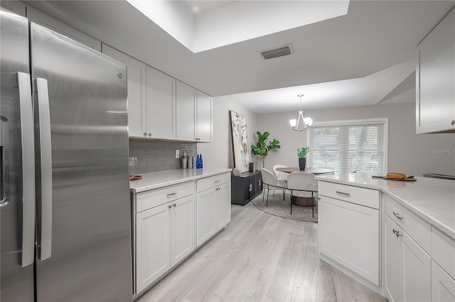 kitchen with hanging light fixtures, white cabinets, tasteful backsplash, stainless steel fridge with ice dispenser, and light hardwood / wood-style floors