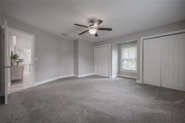 unfurnished bedroom featuring ceiling fan, carpet flooring, and two closets