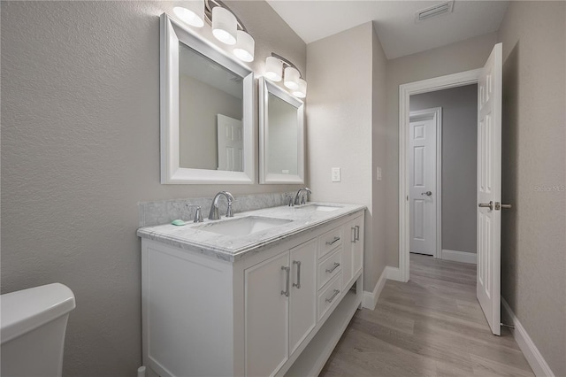 bathroom with wood-type flooring, toilet, and vanity