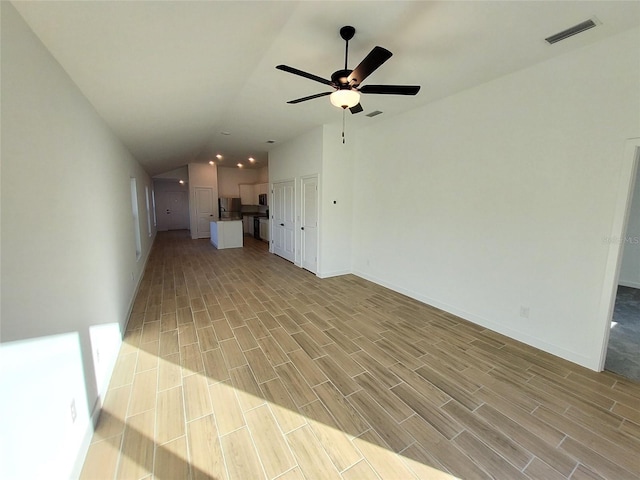 unfurnished living room featuring vaulted ceiling and ceiling fan