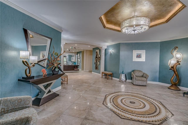 interior space featuring ornamental molding, an inviting chandelier, a raised ceiling, and ornate columns