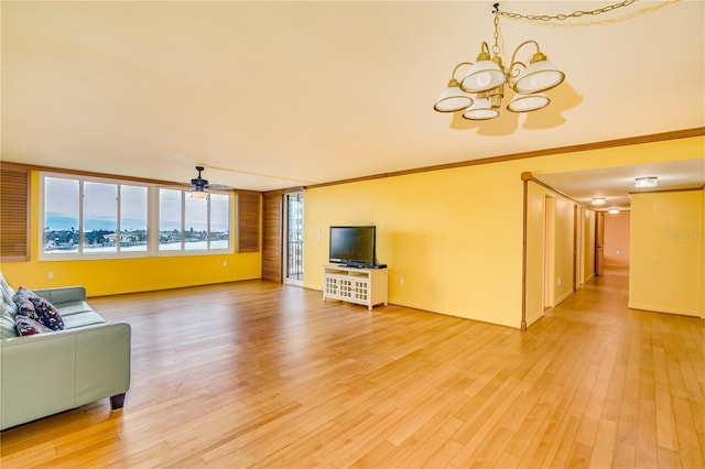 living room featuring hardwood / wood-style flooring, ceiling fan with notable chandelier, and crown molding