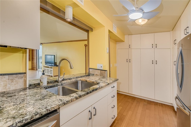 kitchen with light stone countertops, sink, white cabinets, and appliances with stainless steel finishes