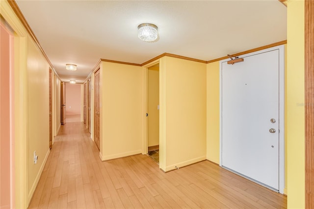 hall with ornamental molding and light hardwood / wood-style flooring