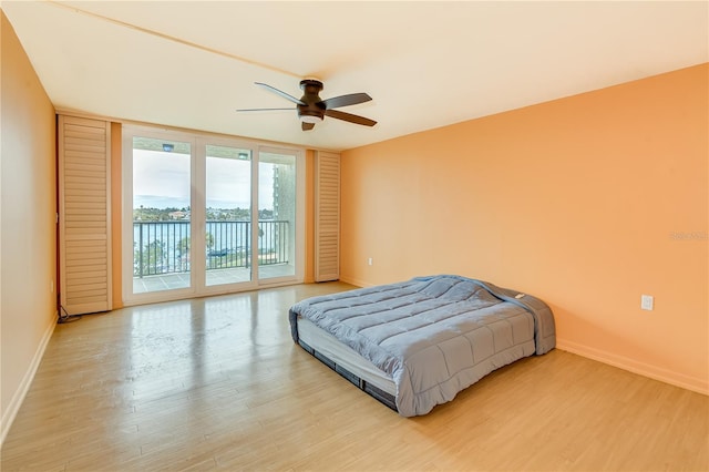 bedroom with light hardwood / wood-style floors, access to exterior, floor to ceiling windows, and ceiling fan