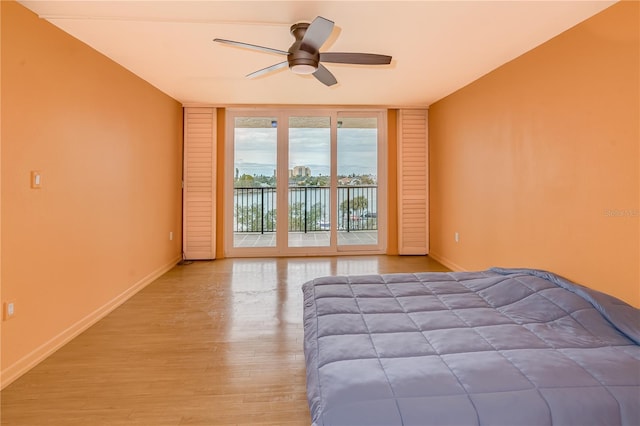 unfurnished bedroom with light hardwood / wood-style floors, access to exterior, floor to ceiling windows, and ceiling fan