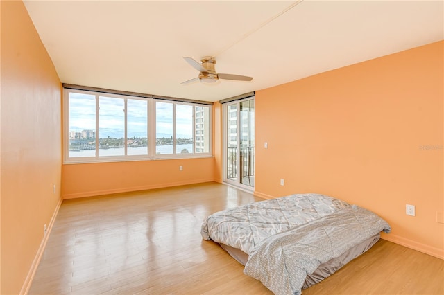 bedroom with ceiling fan, access to exterior, and wood-type flooring