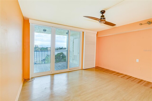 unfurnished room with light hardwood / wood-style floors, ceiling fan, and a water view