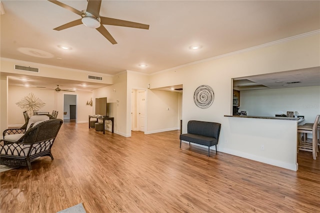 living area with hardwood / wood-style flooring, ceiling fan, and ornamental molding