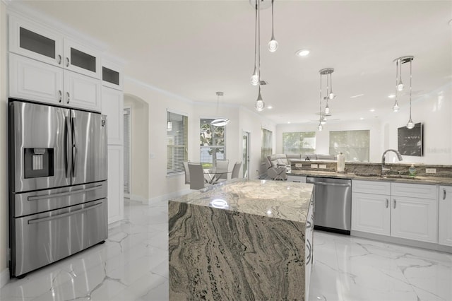 kitchen featuring stone counters, sink, hanging light fixtures, stainless steel appliances, and white cabinets