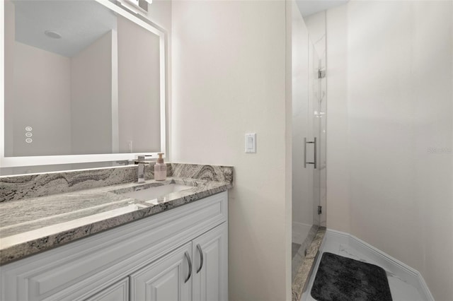 bathroom with a shower with shower door and vanity