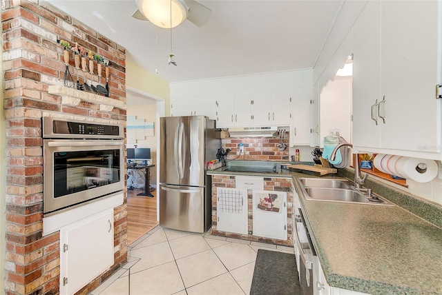 kitchen with sink, light tile patterned floors, appliances with stainless steel finishes, white cabinetry, and extractor fan