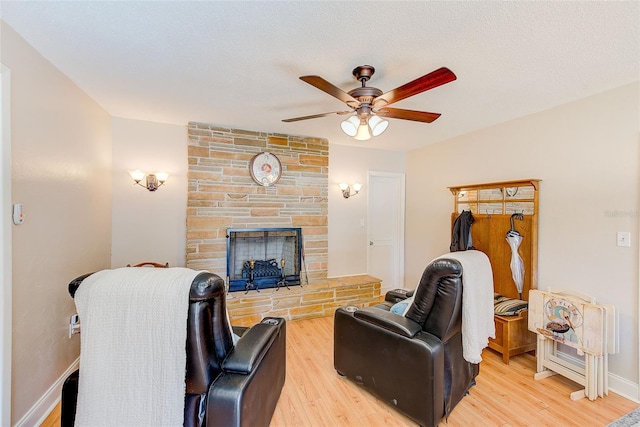 living room featuring a fireplace, a textured ceiling, wood-type flooring, and ceiling fan