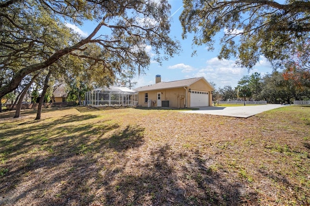 view of yard featuring glass enclosure and a garage