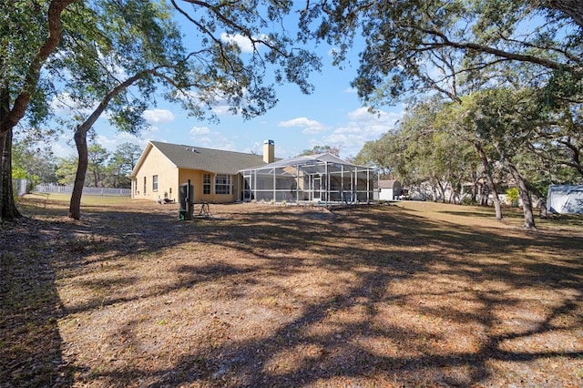 back of house with glass enclosure and a lawn